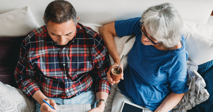 Senior couple sitting on a sofa doing a crossword