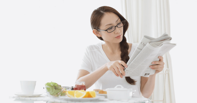 woman-reading-newspaper-at-breakfast